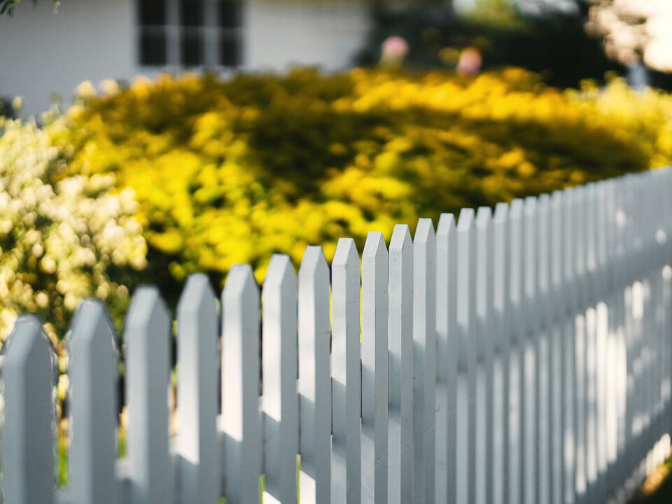 White picket fence along a front-yard garden
