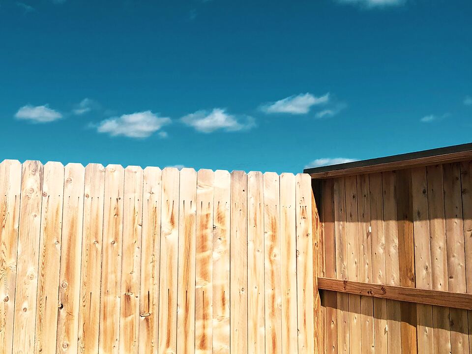 New wood privacy fence under a clear blue sky